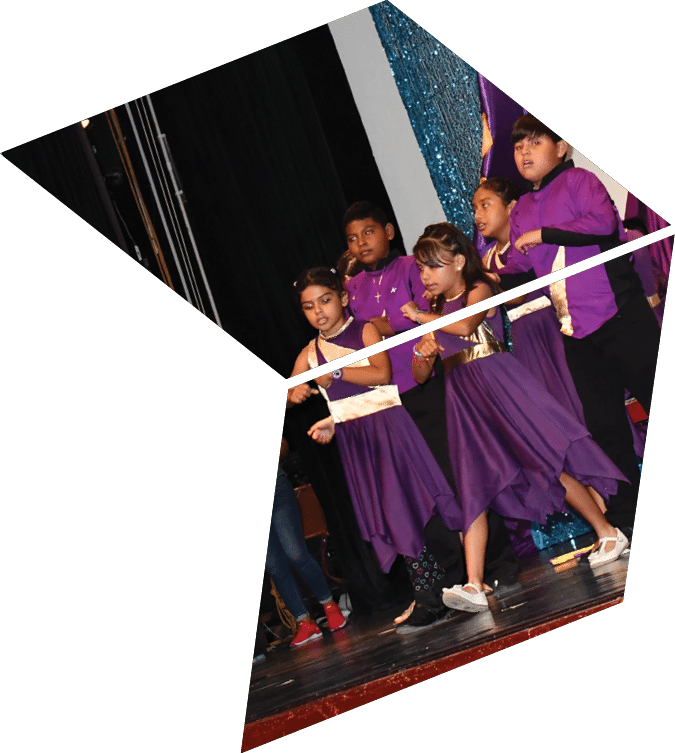 A group of children in purple dresses are performing on stage. Description generated by AI